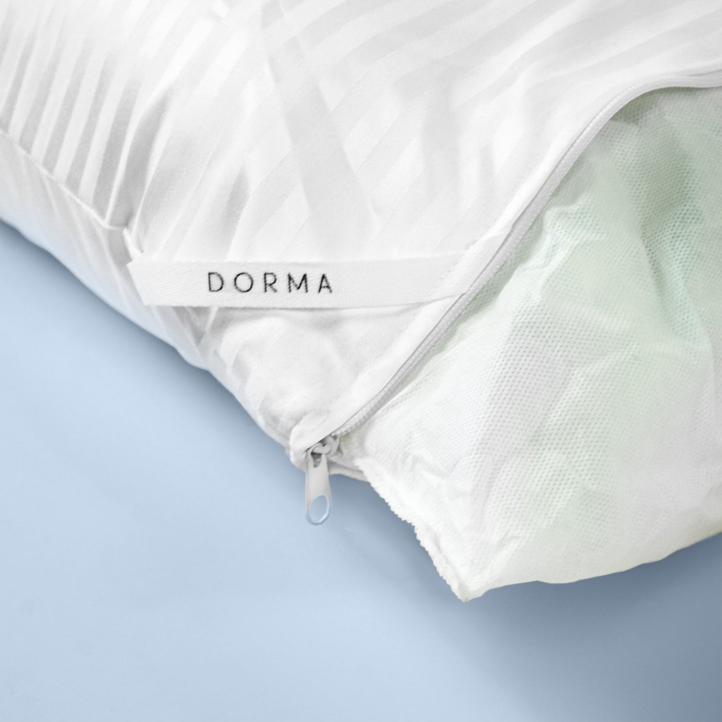 en un fondo azul se encuentra la esquina de una almohada donde se puede mostrar su cierre, etiqueta, y forro.