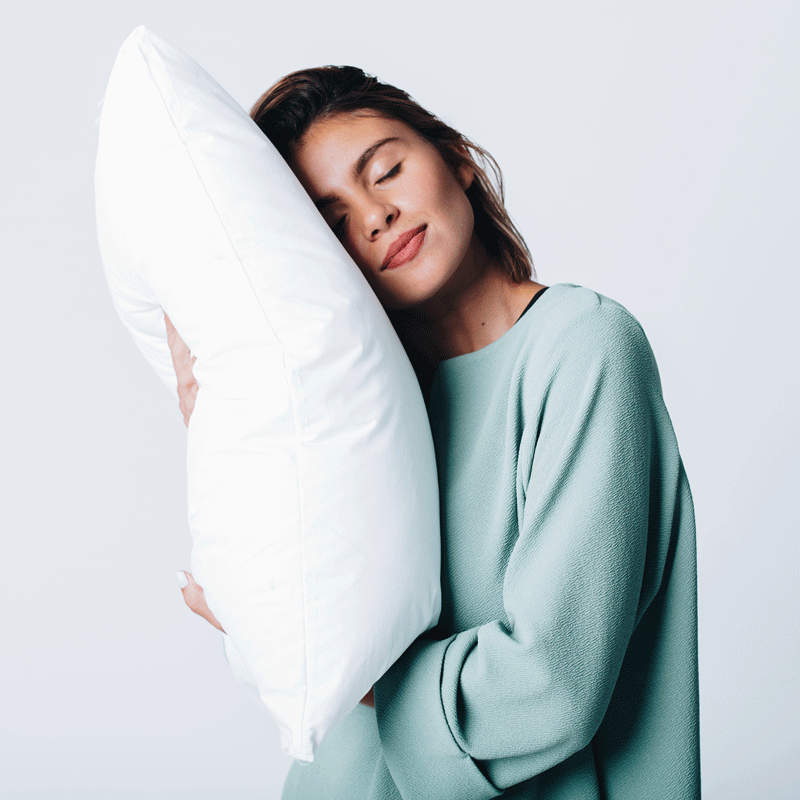 Es una imagen en formato gif donde se muestra una mujer recostando su cabeza en una almohada mientras sonríe.
